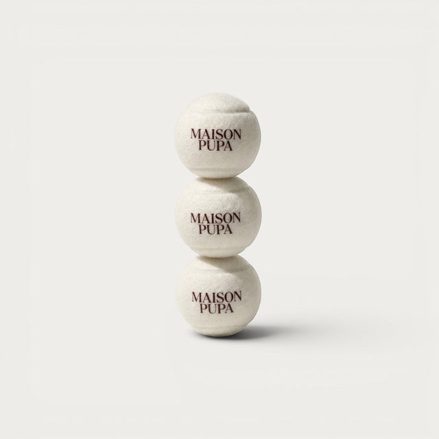 Three Maison Pupa cream felt tennis balls stacked vertically, each featuring a wine-toned brand wordmark.