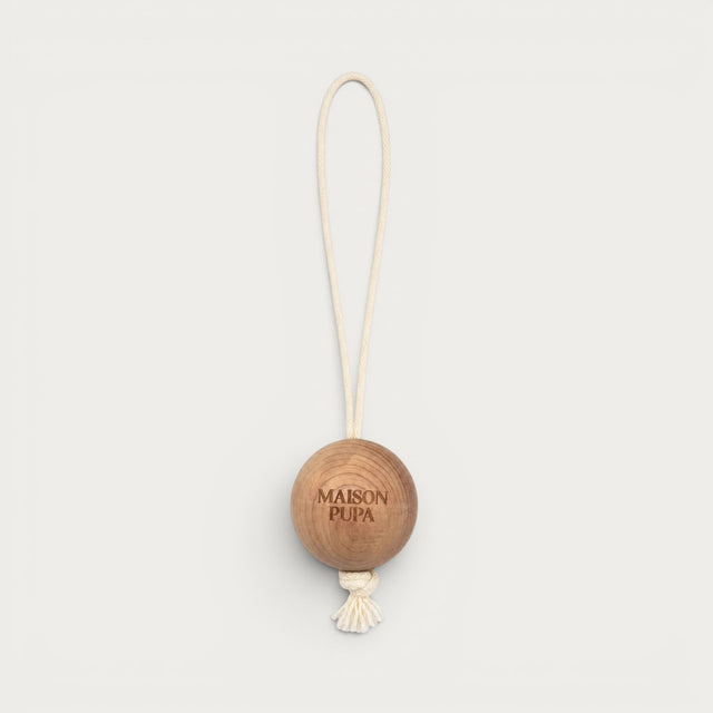 Maison Pupa hanging pet toy featuring a natural cedar wood ball with a cream rope loop and tassel detail.